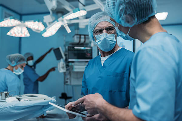 Sala de operaciones con cuatro doctores organizando todo antes de la operación al paciente