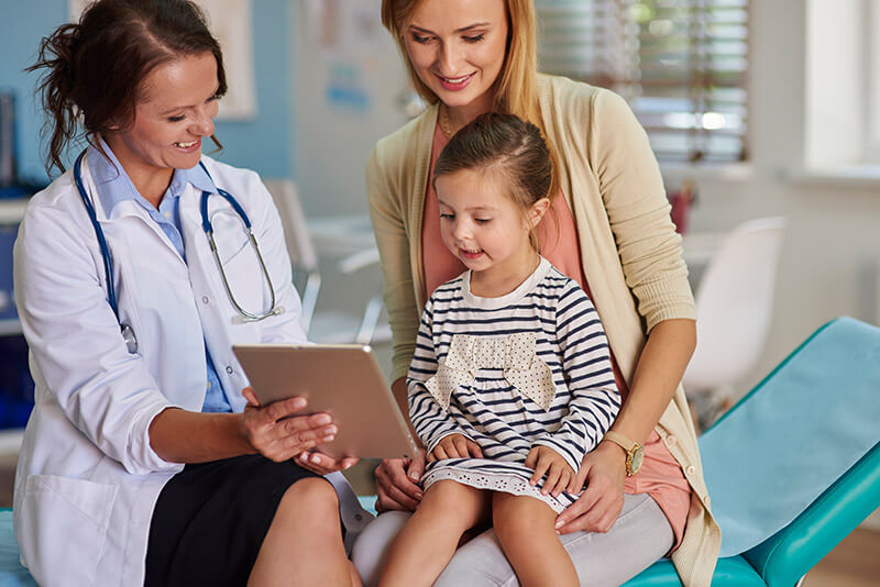 Madre con su hija mirando los resultados médicos junto a la pediatra