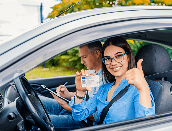 Woman in the driver seat holding a drivers license next to a man holding a notepad