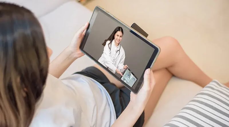 Woman seen from above holding a tablet with an image of a doctor