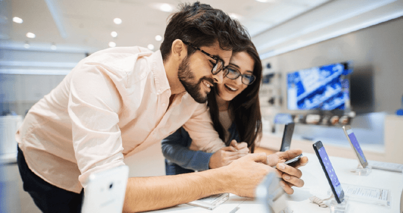 Hombre y mujer con gafas viendo smartphones en una tienda