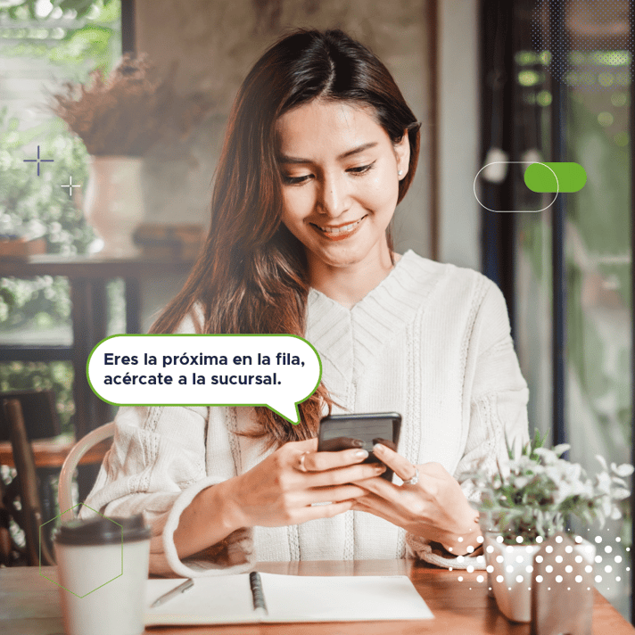 mujer latina viendo una notificacion en su telefono que le informa que su turno se aproxima mientras bebe un café