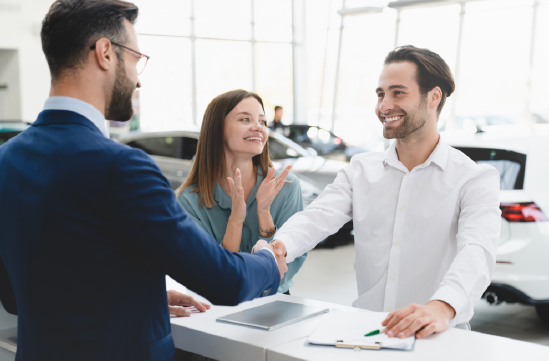 Pareja celebrando la compra de su automóvil en una concesionaria
