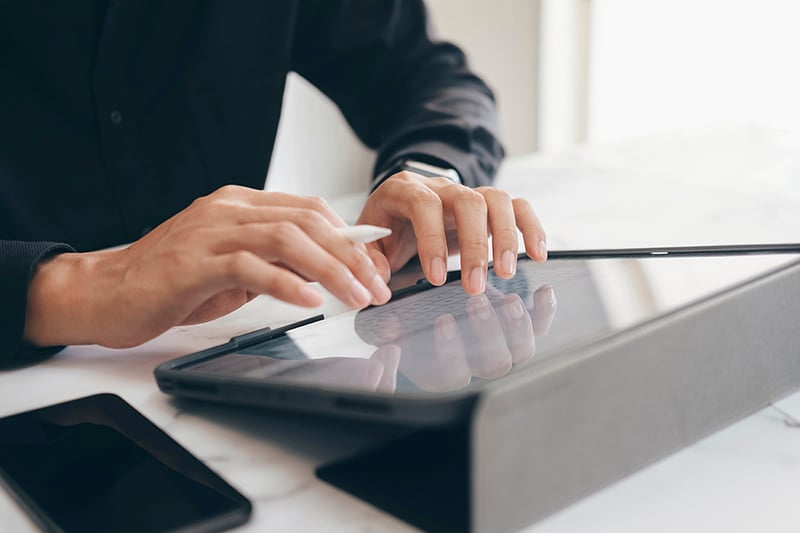 Plano detalle de las manos de una persona digitando sobre una tablet