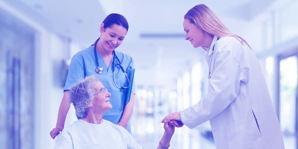 Photograph of a female doctor and nurse attending to an elderly woman in the hospital corridor