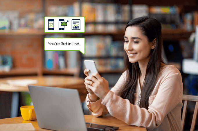 Young woman looking at her phone while waiting in a library