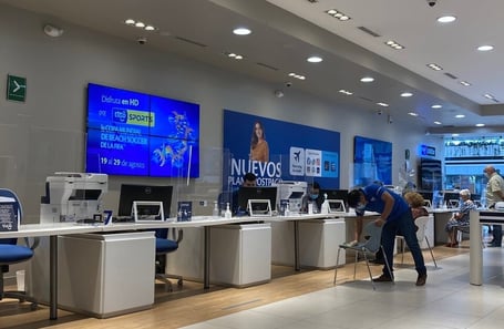 Centro de atención al cliente con personas esperando y siendo atendidas en entorno de telecomunicaciones