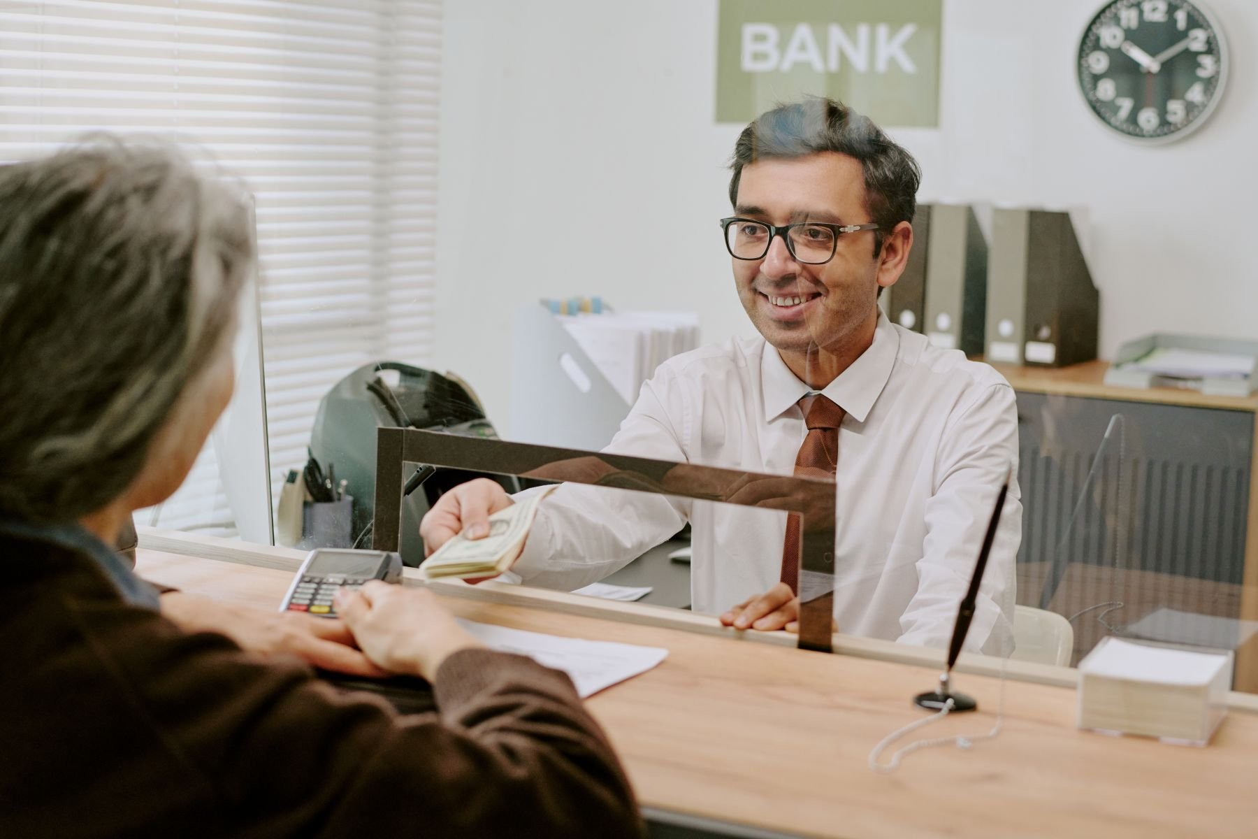 bank-teller-smiling-while-helping-customer-2025-04-06-06-19-23-utc