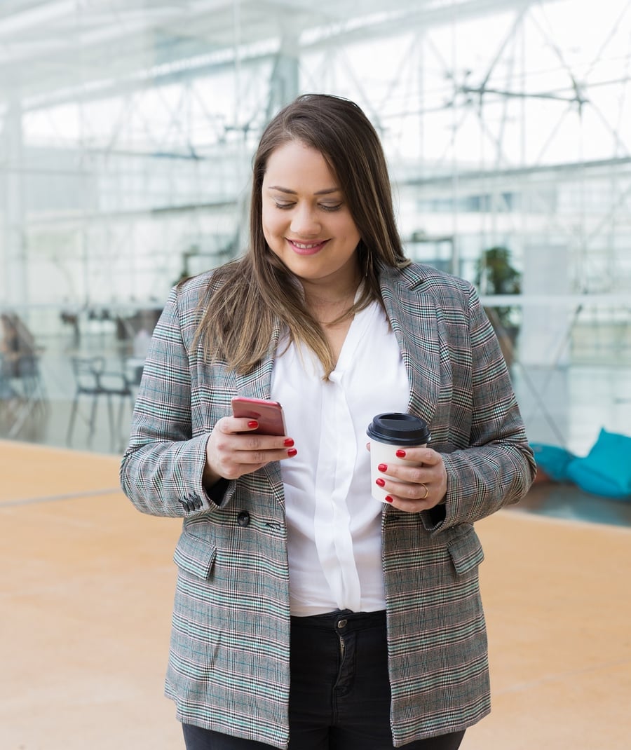 mujer-de-negocios-sonriente-que-manda-un-sms-en-smartphone-al-aire-libre
