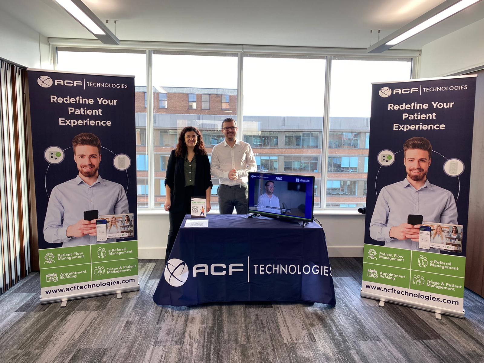 Exposición en Manchester Conferencia de Hospitales Digitales, dos banners una mesa central con logo de ACF y representantes de venta