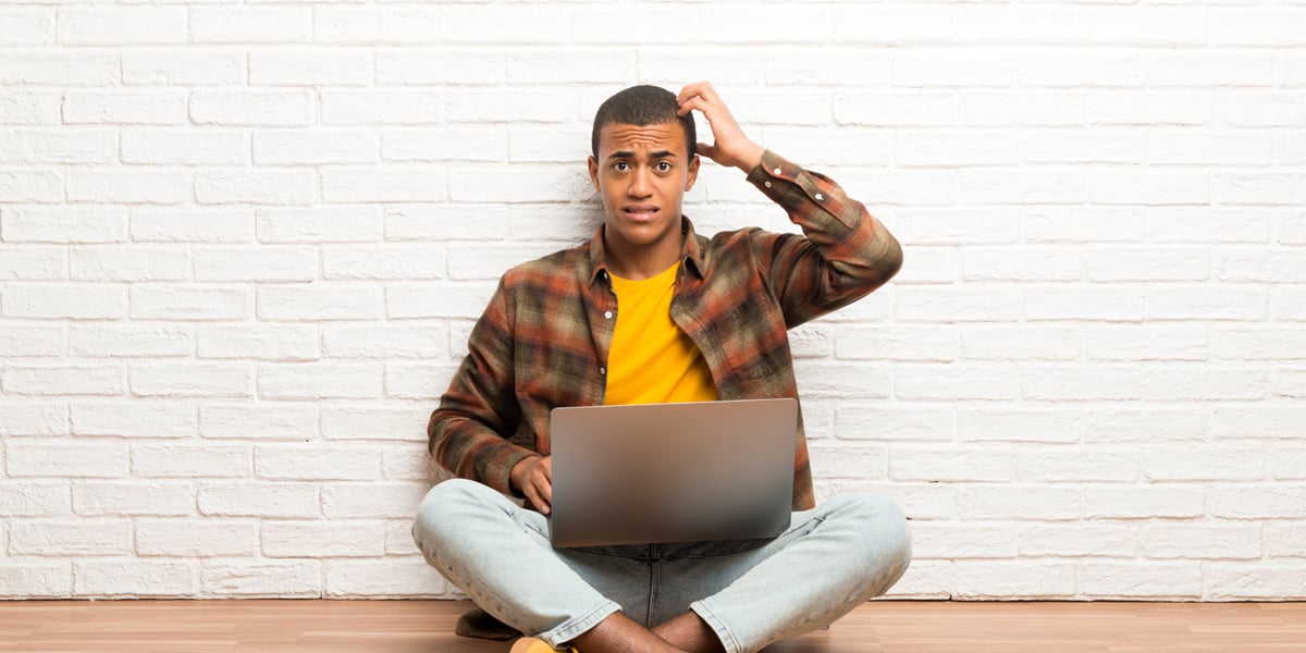 Man scratches head in confusion while learning from laptop