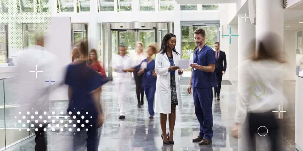 Doctores conversan en sala de espera de hospital con mucha afluencia