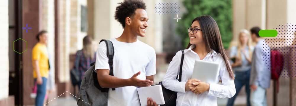 A couple of college students talking and walking smiling through the campus