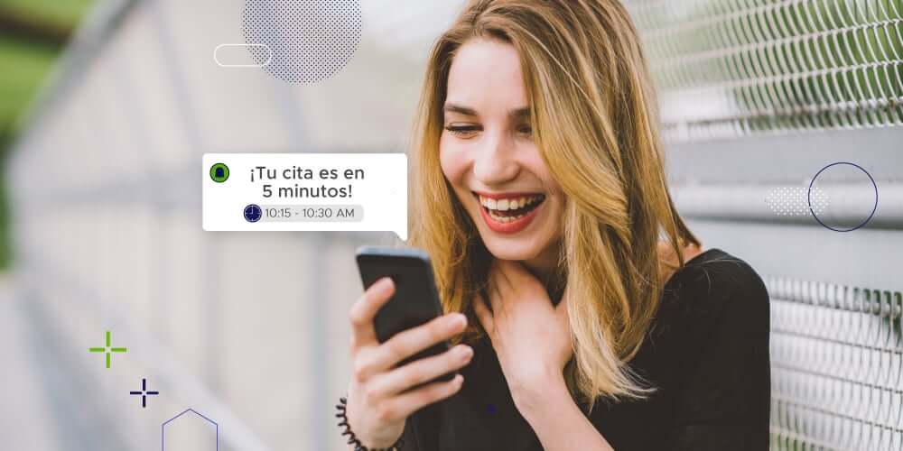 Mujer rubia sonrie al ver un mensaje de sobre su cita programada