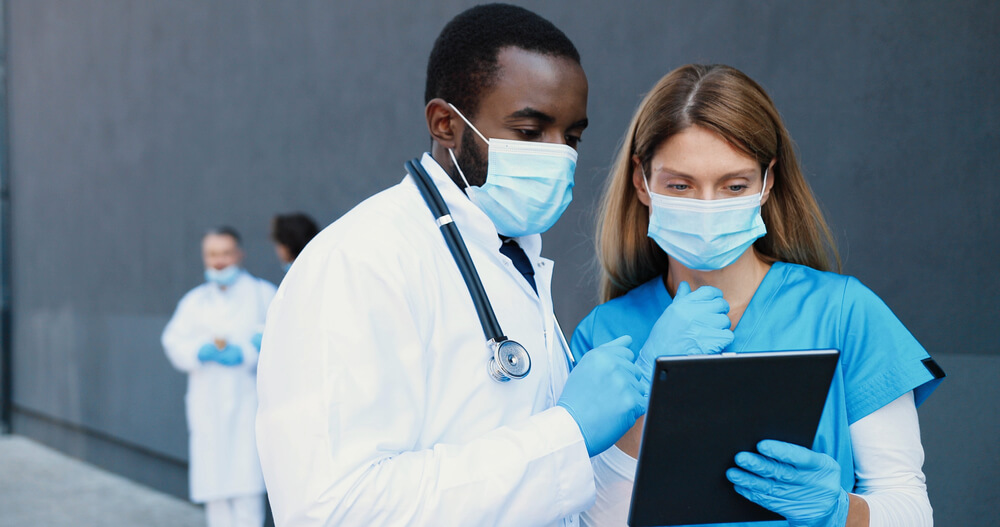 Four doctors with masks and gloves in the photograph two of them checking a device