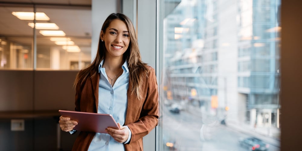 Business woman with tablet by large office window