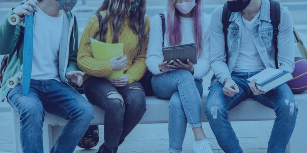 Fotografía de medio cuerpo a cuatro alumnos sentados conversando