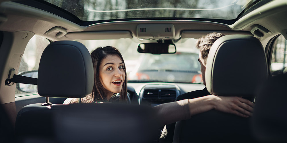 Fotografia de uma mulher ao volante olhando para trás porque o veículo está dando ré