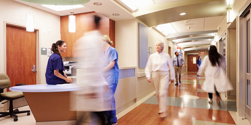 Fotografia de um corredor de hospital com equipe médica em movimento