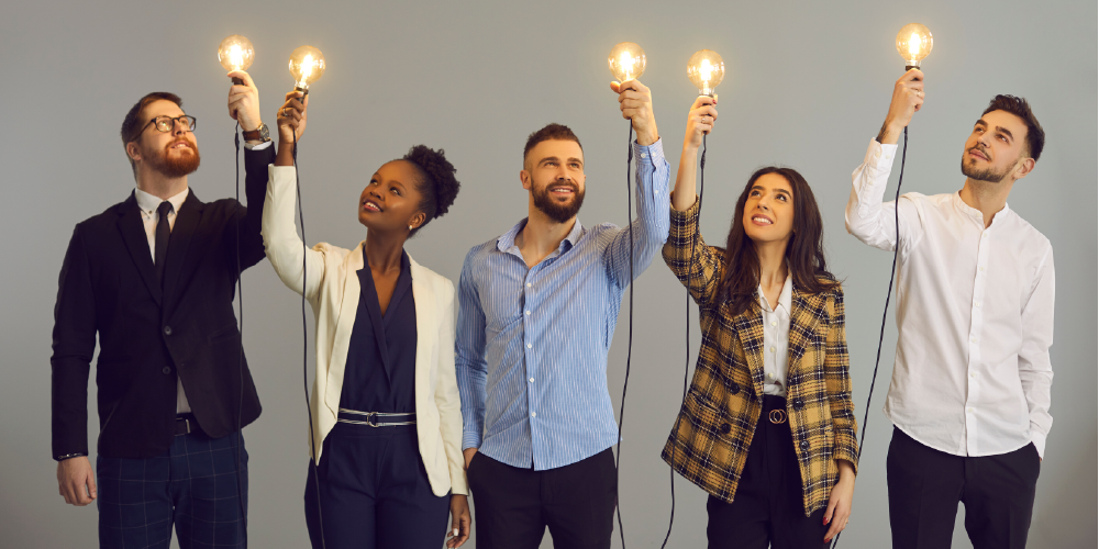 Hombre y mujeres levantando con su mano un bombillo de luz 