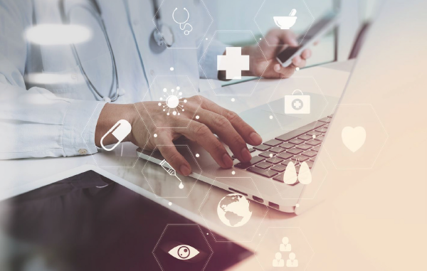 Mãos de um médico trabalhando em um laptop e em um smarphone