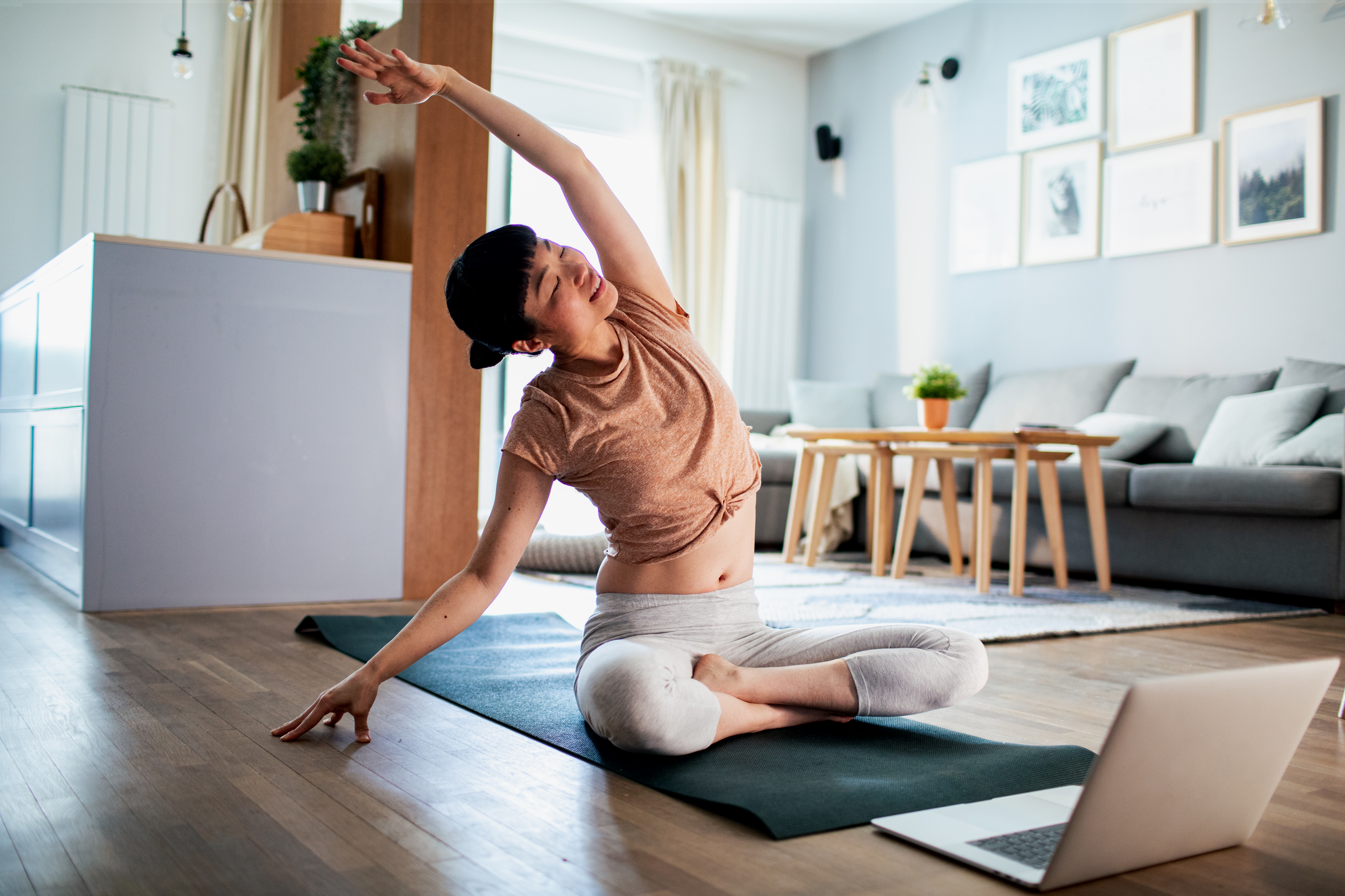 Woman doing yoga from a laptop 