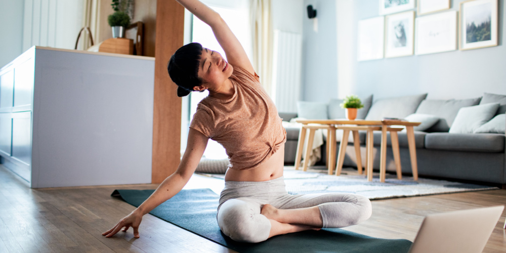 Woman doing yoga with her laptop in front of her. 