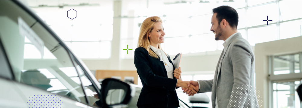 Smiling saleswoman at a dealership shaking hands with a smiling customer