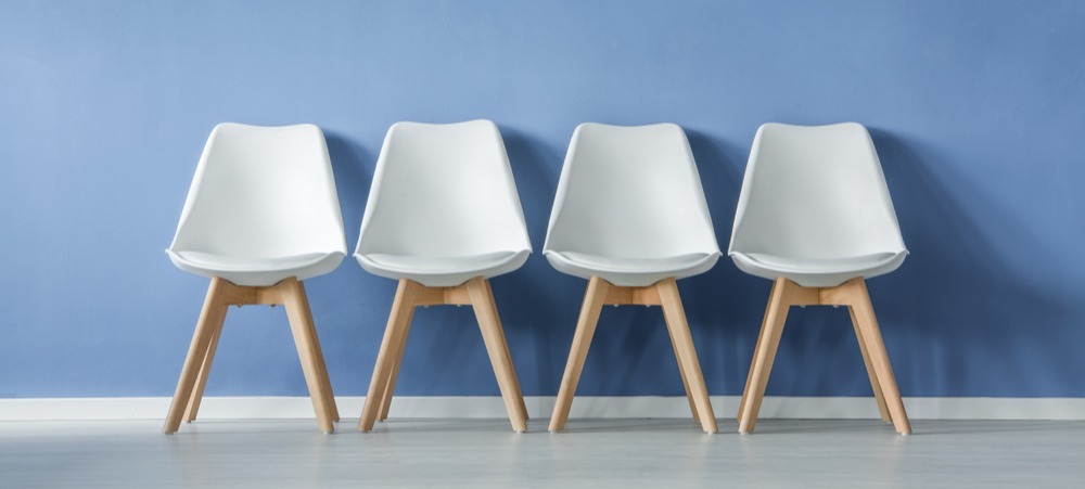 Four empty white chairs in waiting room