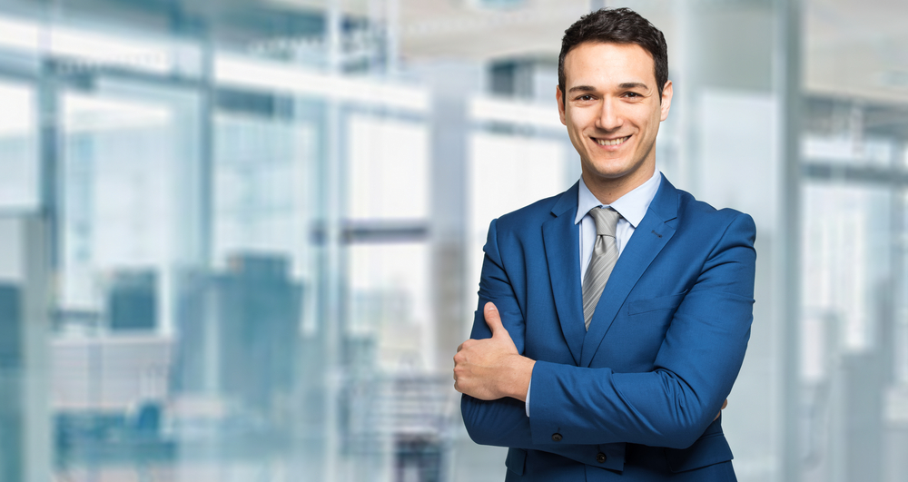 Smiling man in a blue suit at a business office. 