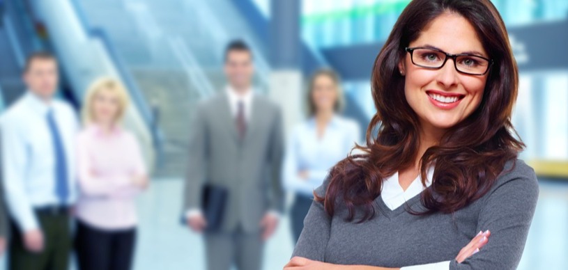 Smiling, confident business woman near fellow employees