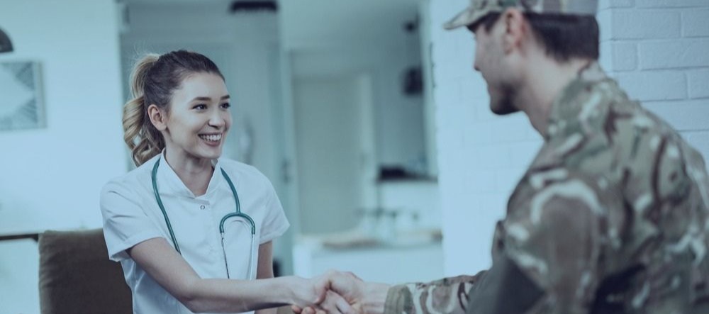Uma médica sorrindo e apertando as mãos de um soldado no Evans Hospital
