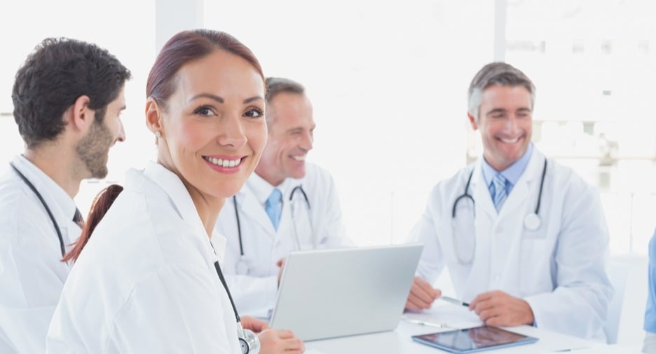 Group of smiling doctors with laptop and tablet