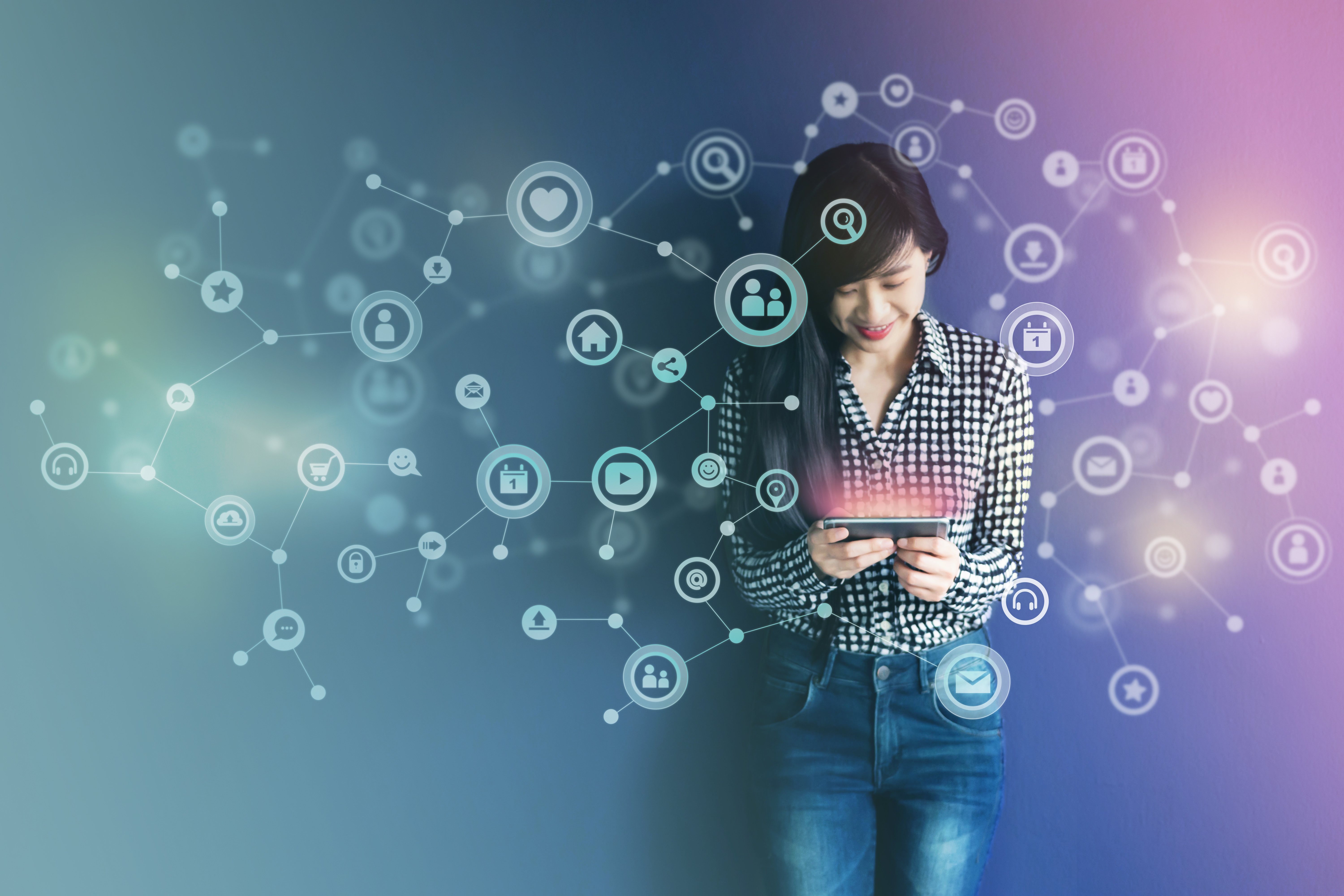Mulher em pé olhando para um tablet em um fundo desfocado de cores azul e lilás, com ícones voadores interconectando com uma rede de comunicação