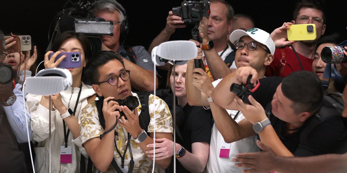 Group of people take pictures and marvel at new Apple Vision Pro on display