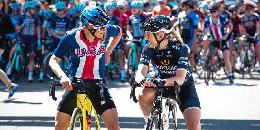 Pair of cyclists talking with one of them wearing Wiggle-branded clothes