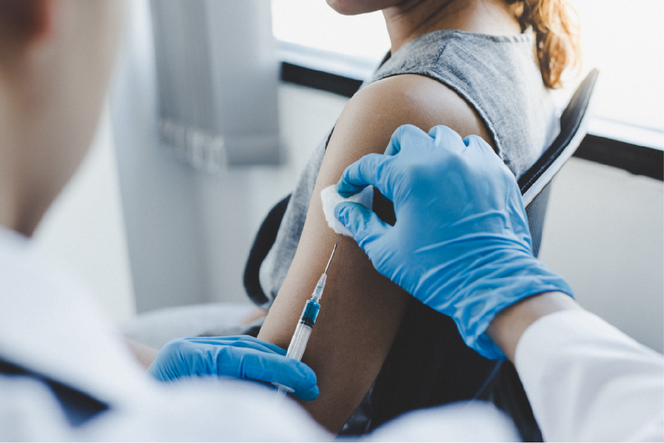 Persona con guantes azules vacunando a paciente