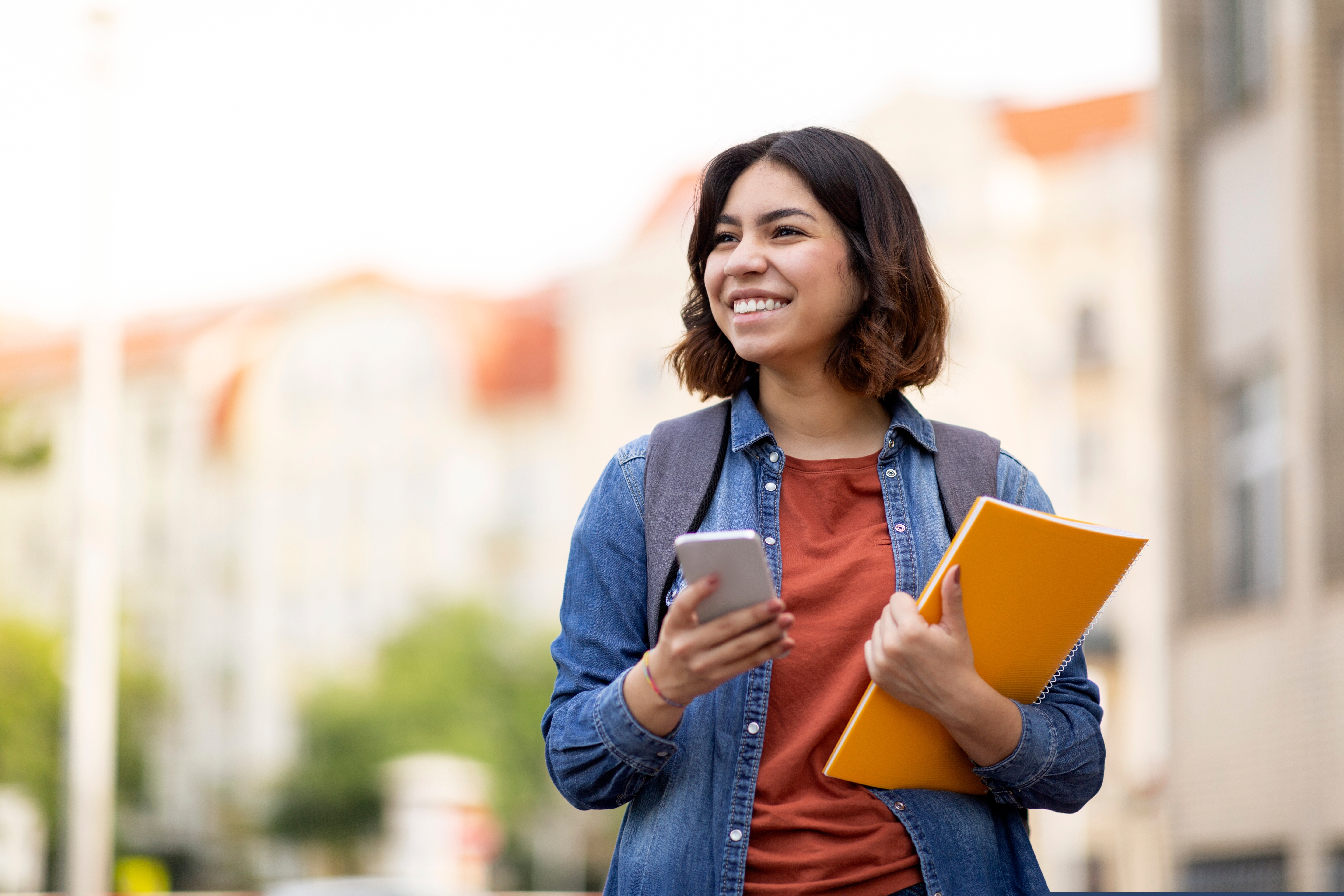 College student with cell phone and orange folder.