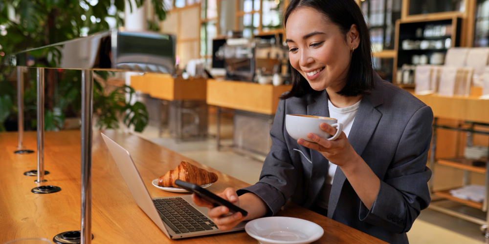 Woman enjoying breakfast out while smiling at her phone